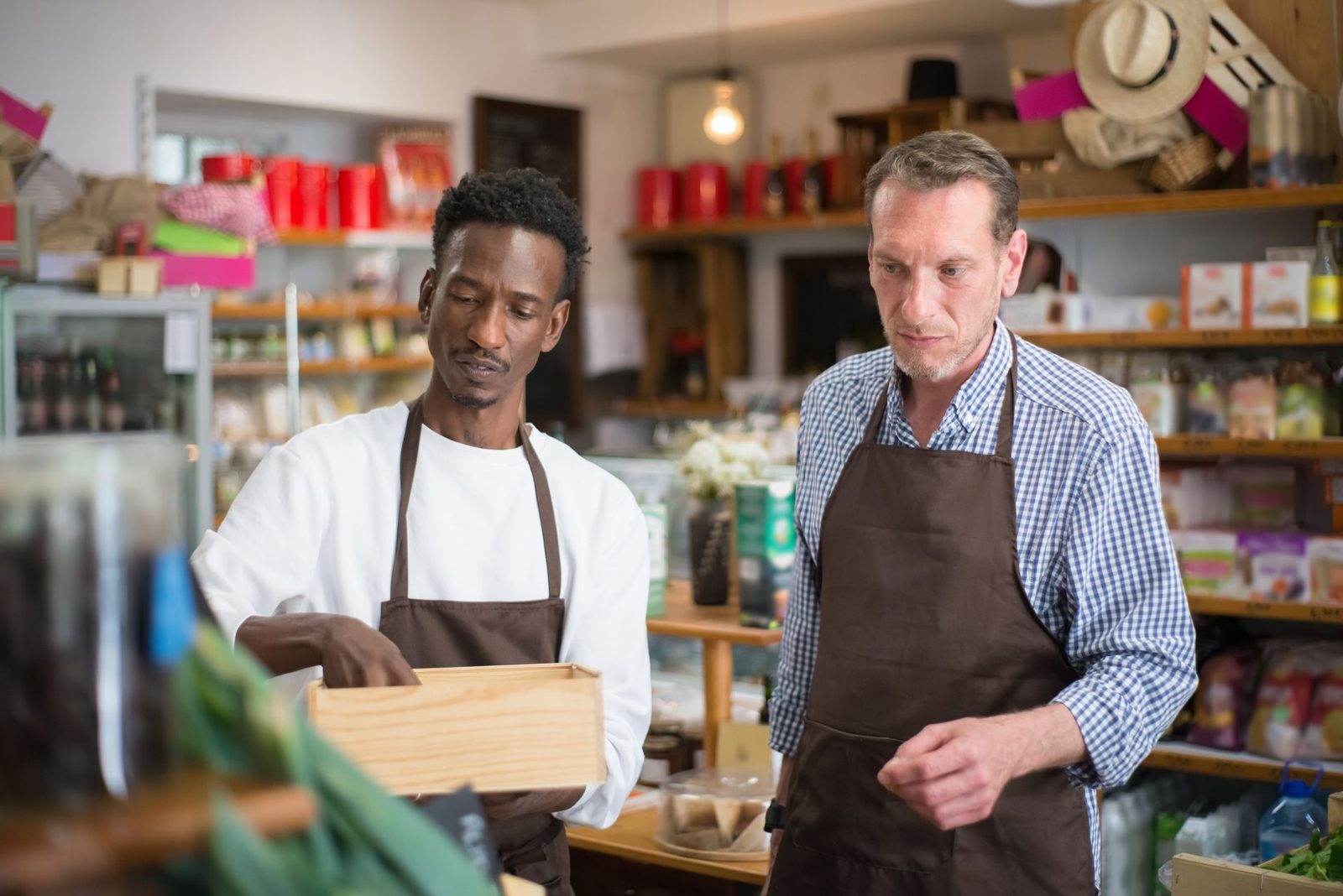 Two shop owners in aprons behind their counter